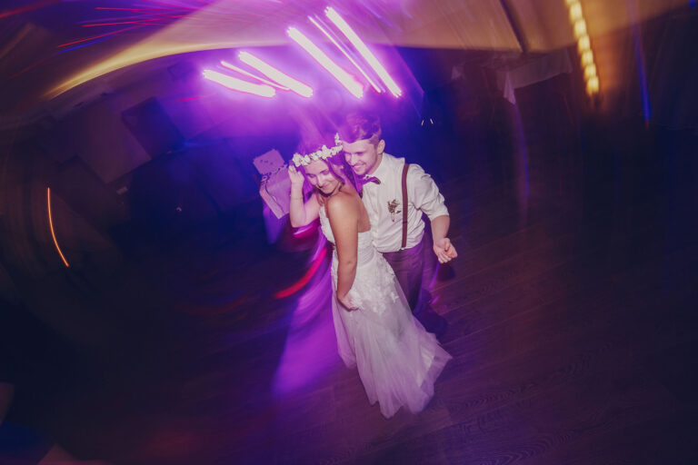 A bride and groom dancing at their wedding reception, captured with dramatic lighting and motion blur.