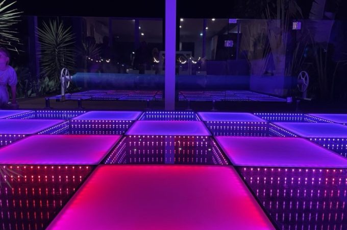 An illuminated, infinity-mirror LED dance floor set up outdoors or in an open-air venue at night.