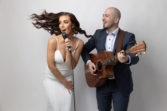 A professional studio photograph of a musical duo performing.