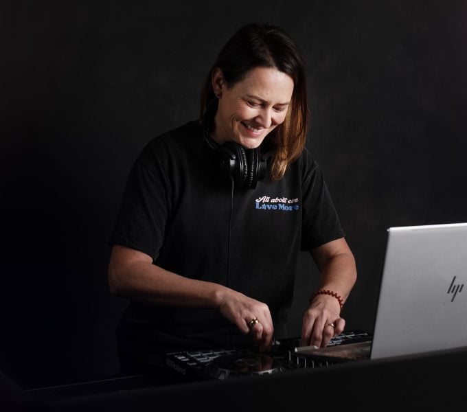 A female DJ performing in a dark setting.