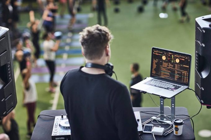 A DJ providing music for a large group fitness class or event.